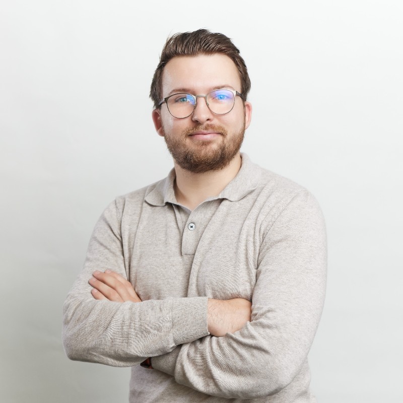 Amaury Lapaque smiling in a red plaid shirt and tortoise shell glasses